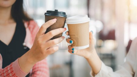 Foto de Concepto de relax empresarial, un primer plano que captura las manos de dos empresarias que sostienen tazas de café para llevar durante una pausa para tomar café en el trabajo - Imagen libre de derechos