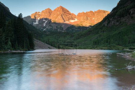 Maroon Bells Sunrise in Mid-Summer.A popular destination for scenic views. the Maroon Bells are appreciated by many people from around the world. This early morning view has a diffused reflection from the moving water on Maroon Lake. 