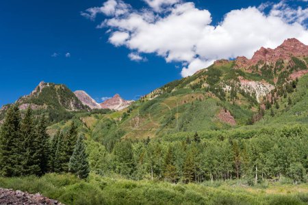 Maroon colorful mountains welcome visitors to wonderful scenic Colorado beauty of mid Summer. Bright green vegetation abound along with the Maroon Colorful Peaks which is viewed from West Maroon Trail south of Aspen Colorado.