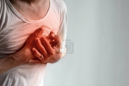 Photo for Asian young man suffering from left sided chest pain. Chest pain can be caused by heart attack, myocardial infarct or ischemia, myocarditis, pneumonia, stress, etc. - Royalty Free Image