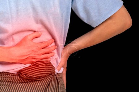 Photo for Asian young man suffering from upper abdominal pain. It can be caused by stomach ache, enteritis, colitis, appendicitis, hepatitis, pancreatitis, food poisoning, etc. - Royalty Free Image