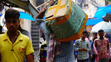 Photo for Select focus on the laborer carrying goods on his shoulder - Royalty Free Image