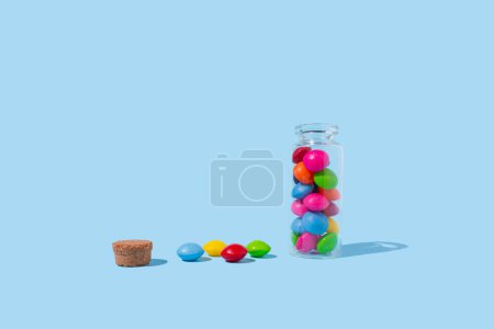 Glass jar with colorful pills on blue background. Concept of medicine, health, pharmacy.