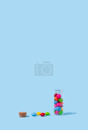Glass jar with colorful pills on blue background. Concept of medicine, health, pharmacy.