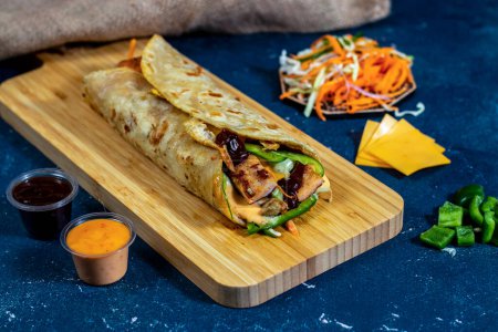 Photo for Egg Cheese Chicken Burger shawarma Wrap with salad dip and sauce isolated wooden board side view of fastfood - Royalty Free Image