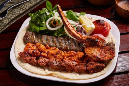 Foto de Bandeja de parrillas mixtas picante con tikka boti kabab, ensalada, limón y pan servido en un plato aislado en la vista lateral de la mesa de comida de Oriente Medio - Imagen libre de derechos