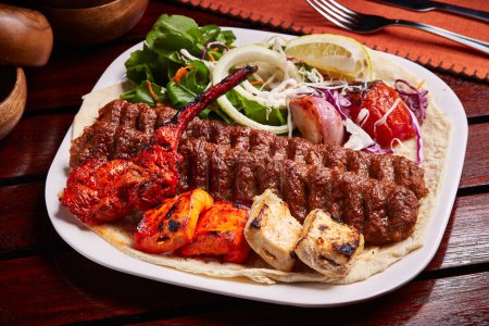Foto de Bandeja Tandoori Grills mixta con tikka boti kabab, ensalada, limón y pan servido en un plato aislado en la vista lateral de la mesa de comida de Oriente Medio - Imagen libre de derechos