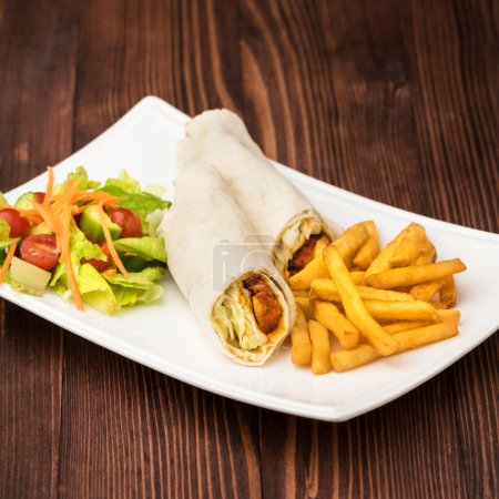 Téléchargez les photos : Rouleau sandwich shawarma tawook chic avec salade et frites servi dans un plat isolé sur la table vue du fastfood - en image libre de droit