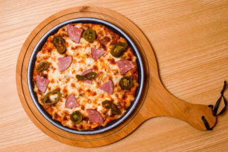 Foto de Pizza flambe servida en tabla de cortar de madera aislada en la vista superior de la mesa de comida rápida italiana - Imagen libre de derechos