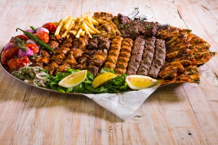 Assorted mix grills with chicken tikka, beef kabab, mutton kebab, wings, boti, malai, chop, shish tawook served in dish isolated on background top view of arabic food
