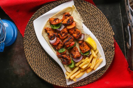 Téléchargez les photos : Shish Tawook ou tikka kabab avec frites, citron et pain servi dans un plat isolé sur un tapis rouge vue du dessus sur la table de la nourriture arabe - en image libre de droit