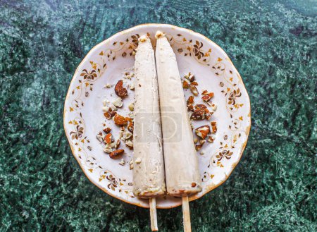Téléchargez les photos : Shahi kulfi ou kulfi comprennent khoya, lait, badam, amande avec bâton servi dans un plat isolé sur fond vue du pakistanais et de la crème glacée indienne - en image libre de droit