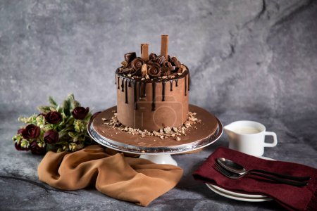 Photo for Chocolate Overloaded Cake with rose flowers, knife and fork served on board isolated on napkin side view of cafe baked food - Royalty Free Image