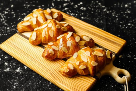 Photo for Almond Croissant topping with nuts served on wooden board side view of french breakfast baked food item - Royalty Free Image