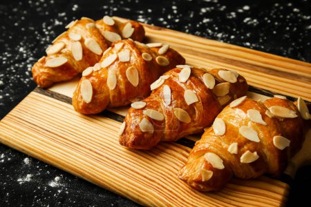 Photo for Almond Croissant topping with nuts served on wooden board side view of french breakfast baked food item - Royalty Free Image