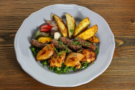 Téléchargez les photos : Mélangez du kofta et du kabab de saumon serti avec des légumes aux pommes de terre, de la tomate, de l'oignon et de la coriandre servis dans un plat isolé sur le côté de la table de la nourriture arabe - en image libre de droit