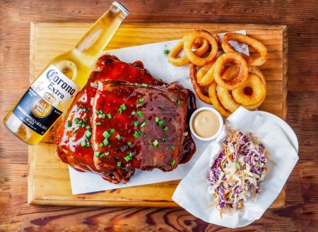 Photo for US baby back ribs with onion rings, salad, corona extra beer 335 ml and mayonnaise dip served in dish isolated on wooden table top view of hong kong food - Royalty Free Image