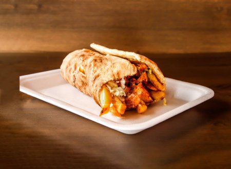 Téléchargez les photos : Enveloppement shawarma de poulet afghan servi dans un plat isolé sur fond en bois vue latérale des épices indiennes et de la nourriture pakistanaise - en image libre de droit