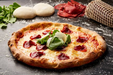 Photo for Bresaola and Rocket Pizza isolated on dark background with raw food top view of italian fastfood appetizer - Royalty Free Image