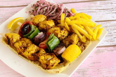 Photo for Joojeh Kabab with Skewer and shahlik with lemon, onion and french fries served in dish isolated wooden table top view of tandoori grill bbq food - Royalty Free Image