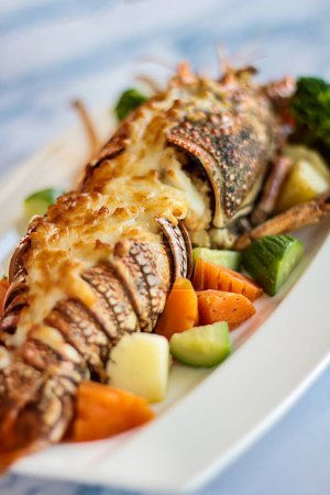 Grilled LOBSTER THERMIDOR served in dish isolated on table closeup top view of grilled seafood