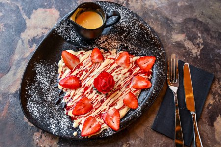 Photo for Crusted strawberry Crepe with white chocolate with whipped cream, knife and fork served in dish isolated on dark background closeup top view of cafe baked dessert food - Royalty Free Image