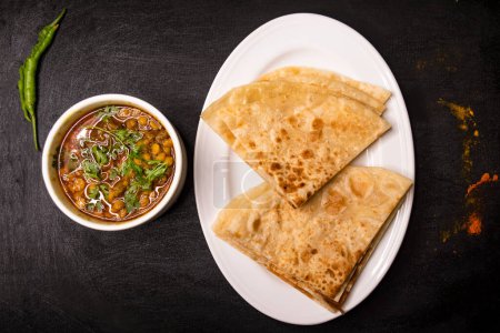 paratha mit dal chana oder chanay serviert in Gericht isoliert auf dunklem Hintergrund Draufsicht indische Gewürze, bangladeshi und pakistanisches Essen