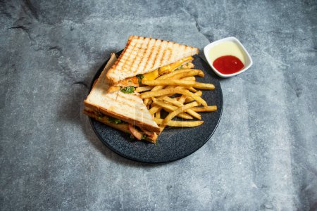 Grilled chicken sandwich with french fries and mayo dip sauce served in plate isolated on background top view of breakfast food indian spices