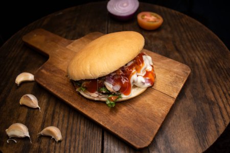 Pita Pocket Sandwich relleno de tomate, cebolla, pollo, mayonesa y ketchup aislado en tablero de madera vista superior de especias de comida rápida árabe