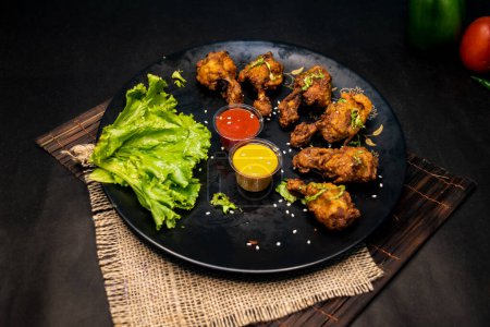 Tandoori Chicken Lollipop mit Mayo-Dip-Chili-Sauce serviert in Gericht isoliert auf Serviette dunklen Hintergrund Draufsicht auf indisches Fastfood