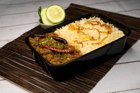 Photo for Achari beef pulao biryani rice with cucumber and lemon slice served in dish isolated on wooden table side view of bangladeshi and indian spicy food - Royalty Free Image