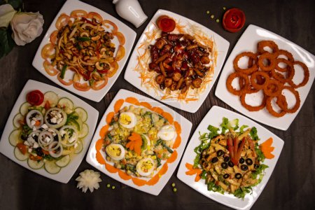 Assorted salads variety with chicken vegetable cashew nut salad, classic Greece salad, russian salad, grilled chicken salad, munchies and fried onion rings served isolated top view of healthy food