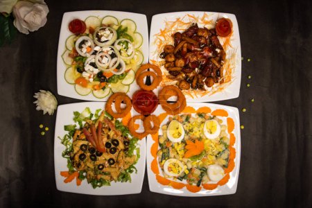Verschiedene Salate Sorte mit Hühnergemüse Cashewnusssalat, klassischer griechischer Salat, russischer Salat, gegrilltes Huhn, munchies, gebratene Zwiebelringe serviert isolierte Nahaufnahme von oben Ansicht von gesunden Lebensmitteln