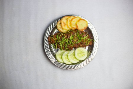 Spicy Beef chaap with tomato and cucumber served in plate isolated on background top view of bangladeshi, indian and pakistani traditional spicy food