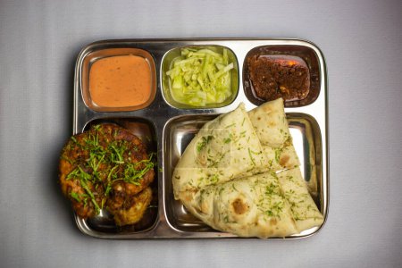 Chicken chaap with garlic nan, chuntney, sauce and chilli dip served in thali platter isolated on background top view of bangladeshi food set menu
