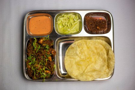 Chicken Masala chaap with Lucchi, chuntney, sauce and chilli dip served in thali platter isolated on background top view of bangladeshi food set menu