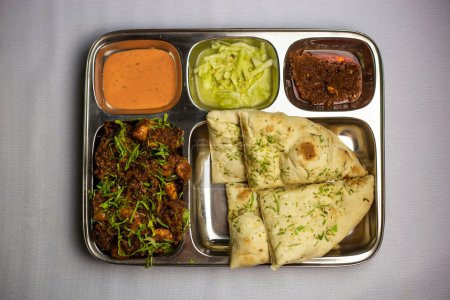 Chicken Masala chaap with garlic nan, chuntney, sauce and chilli dip served in thali platter isolated on background top view of bangladeshi food set menu