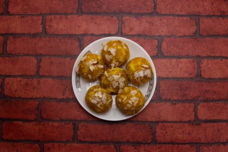Mawa Laddu sweet topping with almonds served in plate isolated on background top view of bangladeshi dessert food