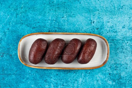 Gulab Jamun, kalo jam or mohan served in tray dish isolated on blue background top view of indian, pakistani and bangladeshi sweet food