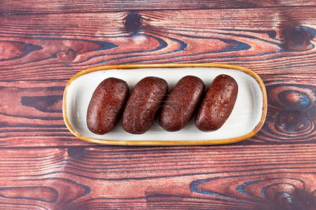 Gulab Jamun, kalo jam or mohan served in tray dish isolated on wooden background top view of indian, pakistani and bangladeshi sweet food