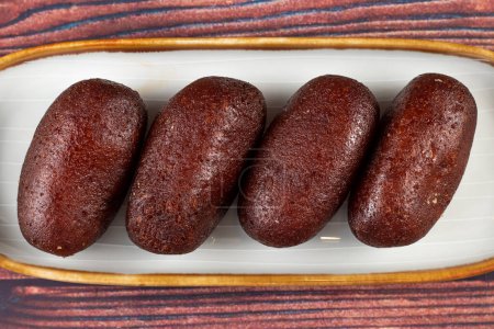 Gulab Jamun, kalo jam or mohan served in tray dish isolated on wooden background closeup top view of indian, pakistani and bangladeshi sweet food