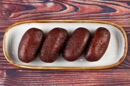 Gulab Jamun, kalo jam or mohan served in tray dish isolated on wooden background top view of indian, pakistani and bangladeshi dessert food