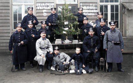 Photo for Belgium, 1914: Colorized photo. Christmas in the First World War of German soldiers in uniform away from home with a child and two dogs. Posing for the camera around the Christmas tree in color. - Royalty Free Image