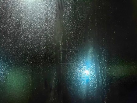 Photo for Rainwater flows down the window pane creating a blurry outside reflection. suitable for backgrounds, presentations and social media. - Royalty Free Image