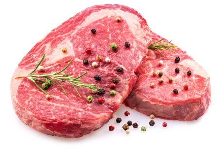 Foto de Raw ribeye steaks with peppercorn and rosemary isolated on white background. Closeup. - Imagen libre de derechos