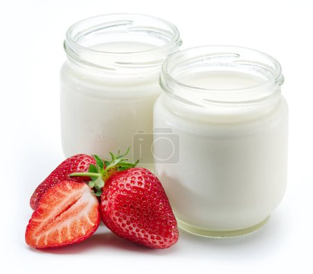 Foto de Two jars of homemade organic yoghurt and fresh strawberries near them on white background. - Imagen libre de derechos