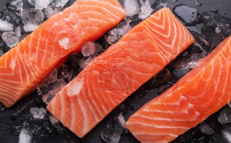 Saumon, tranches de filet de saumon frais réfrigérées en cubes de glace sur planche à découper en ardoise graphite.
