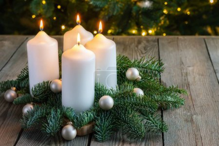 Advent wreath with four white candles, fir branches on wooden background. Sunday December. Traditional diy Christmas decoration, holidays background.