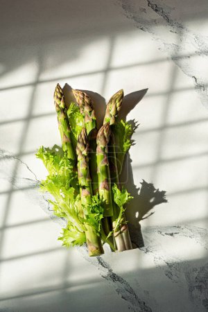 Téléchargez les photos : Asperges vertes fraîches sur fond de marbre blanc. Le concept de légumes sains, la nourriture. Photo conceptuelle. - en image libre de droit