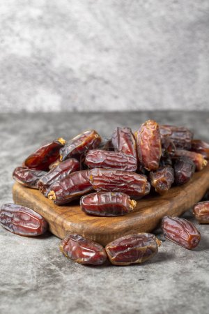 Photo for Date fruit on a dark background. Organic pile of medjoul dates on a wood serving board. Ramadan food. close up - Royalty Free Image
